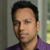 A headshot of Abhishek Jain wearing a purple and blue checkered shirt