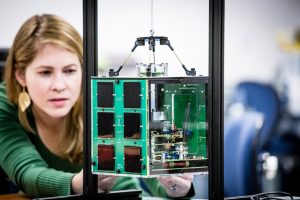 A woman working on a nano satellite model.