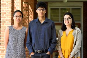 Kathy Le, Vinay Ayyappan, and Julia Costacurta standing in the corridors of the campus, while posing for a picture.
