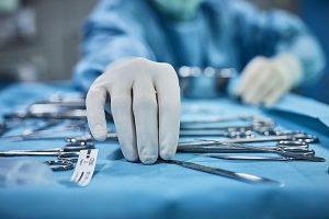 A clinician is taking the surgical tools from the tray while wearing gloves.