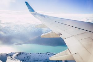 An airplane's wing that is flying over hills covered in snow.