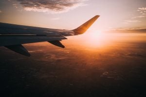 An airplane's wing with the sun rising in the background.