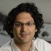A headshot of Vikram Chib wearing a checkered white shirt.