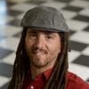 A headshot of Joshua Vogelstein wearing a red shirt and a gray cap.
