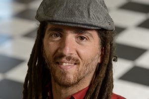 A headshot of Joshua Vogelstein wearing a red shirt and a gray cap.