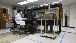 A man wearing lab coat and protective eye gear working in laboratory.