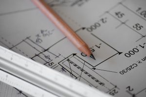 A pencil and a ruler on a paper with engineering diagrams on it.