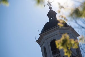 Top part of a building on the campus with a weather vane on the top, on a sunny day.