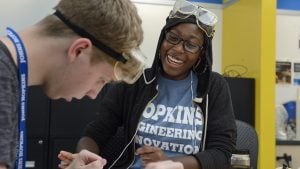 Two students reviewing work together. Female student is smiling, wearing 'Hopkins Engineering Innovation' shirt.