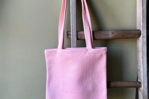 A pink tote bag hanging on a ladder