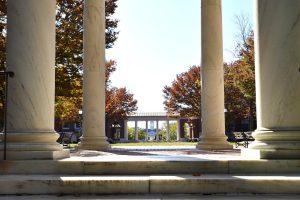 4 pillars of a colonnade in front of a garden of the campus