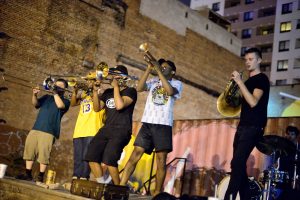 A brass band with a drummer plays on stage at the Ynot Lot in Charles Village.