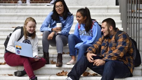 Seven Johns Hopkins students walk on a brick pathway on their way to class