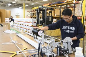A student crafts a cane on a filament winding machine. 