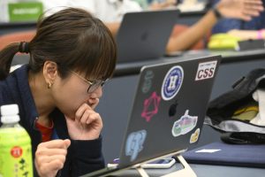 A student leans in, looking at their laptop screen.