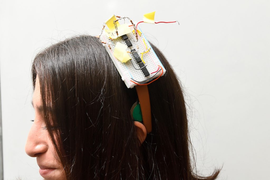 A close-up of the Cerebri headband on a student's head, showing a breadboard and sensor. 