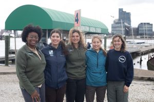 Five members of the team pose for a group photo along the Baltimore waterfront. 