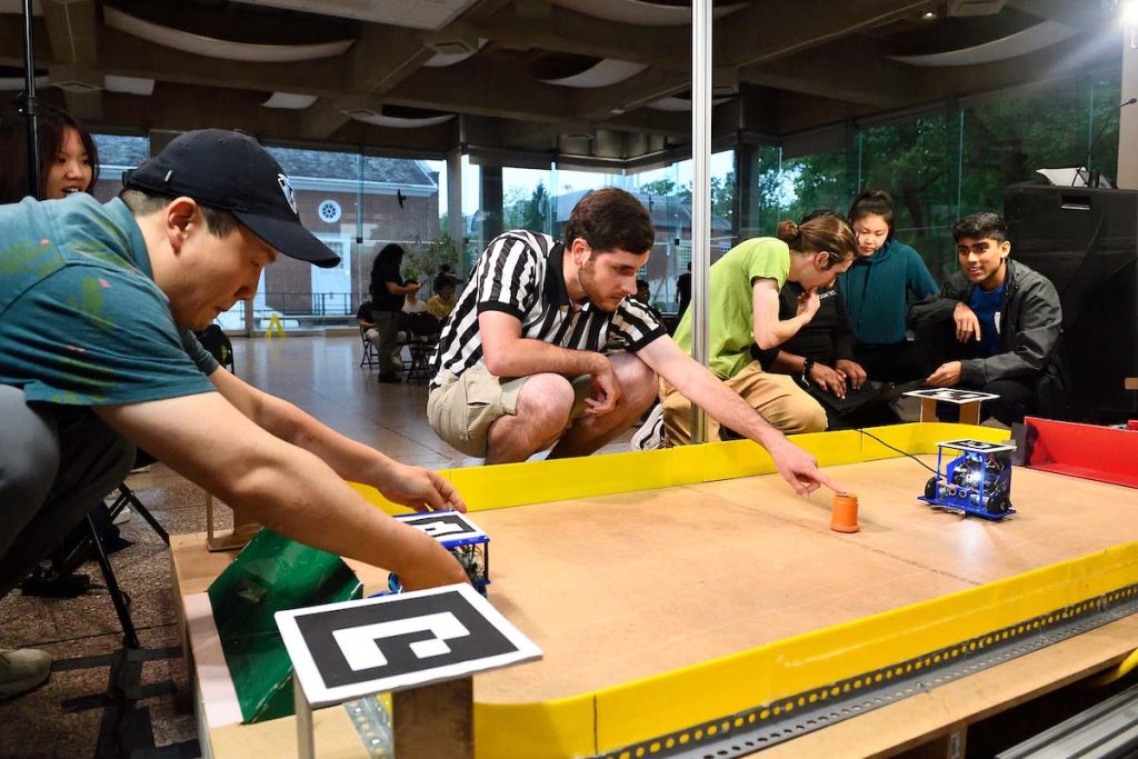 Competitors set up their robots on a simulated hockey rink.