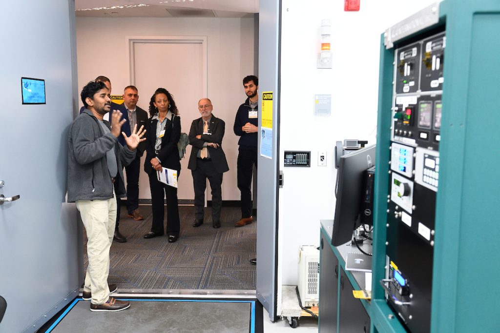 A tour guide stands in a doorway showing tour participants some of the equipment and tools of the MCP.