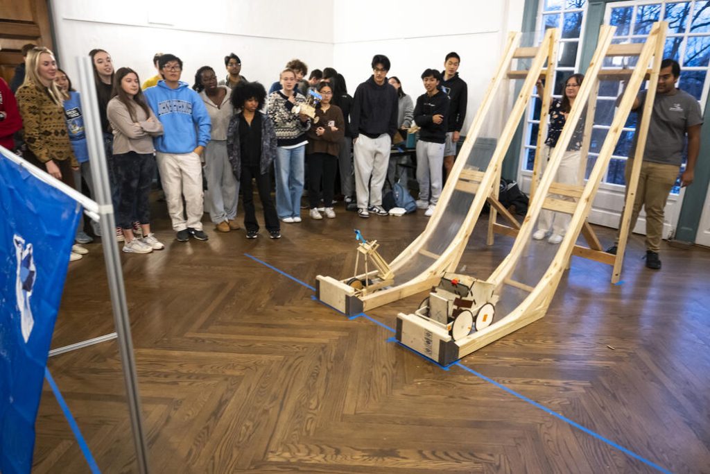 Students gather around to watch two structures perform