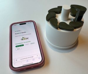 A photo of the scentcare site showing on a cell phone, next to the model.