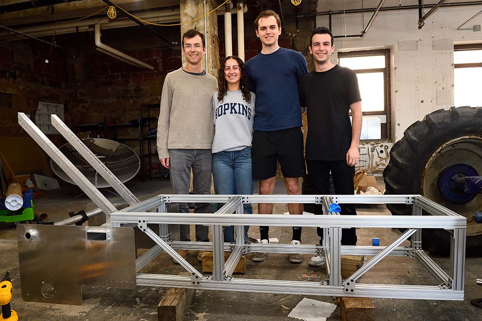 Group photo of team members behind their large steel framed design.