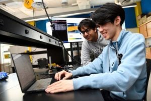 Two students collaborate at a laptop. 
