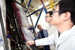 A research team, including Professor Gernay, collaborates around a structural fire testing rig in the lab.

