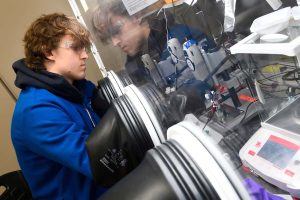 Liam McMullin operates equipment inside a glovebox, used to safely handle materials for solid-state lithium battery research.

