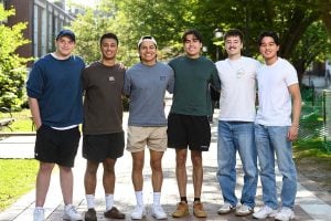 6 members of the team post for a photo outdoors on campus.