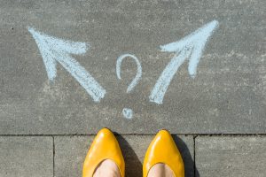 Yellow shoes standing before two arrows going opposite directions