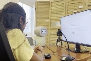 A woman sitting in front of the computer and robot during the research study.