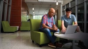 Sanjeev Khudanpur and Drew Prinster look at a laptop. 