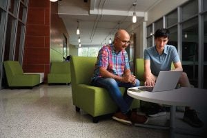 Professor Sanjeev Khudanpur sits beside student, Drew Prinster and looks at the student's laptop