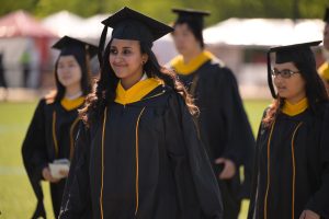 Radiant graduate in cap and gown walking in procession with fellow graduates