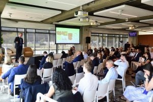 Jordan Green speaks on a stage in front of a large group at the Innovation Summit