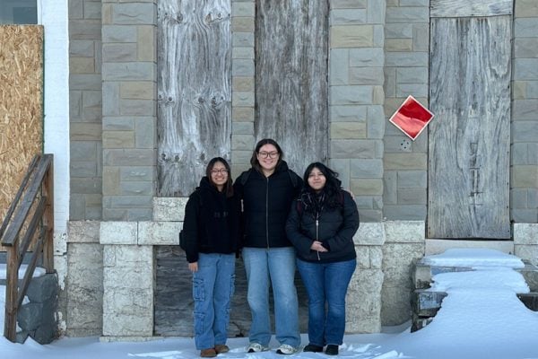 Team member group photo outside the boarded-up rowhouse with snow on the ground. 