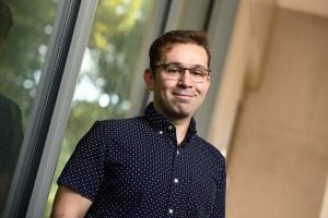 Professional photo of Daniel Khashabi taken outside a campus building with windows behind him. 
