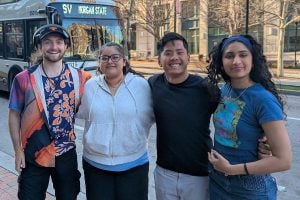 4 team members pose for a photo in Baltimore City with a bus behind them